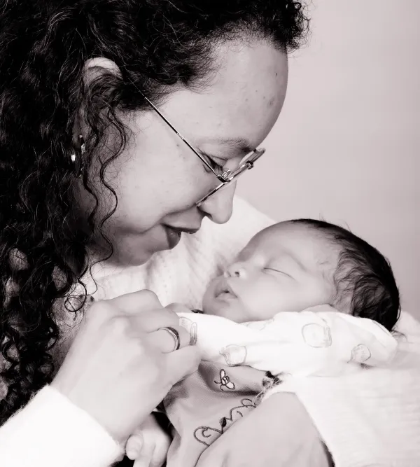 Black-and-white portrait of a mother kissing her newborn baby
